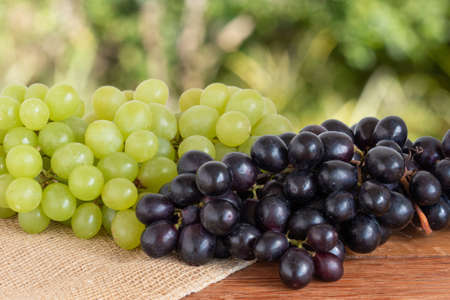Green and purple grapes on wooden mes with blurred backgroundの写真素材