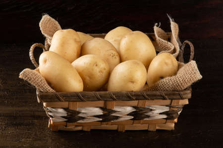 Pile of potatoes in the basket on rustic backgroundの写真素材