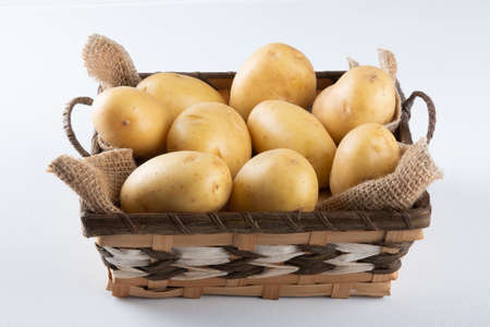 Pile of potatoes in the basket on white backgroundの写真素材