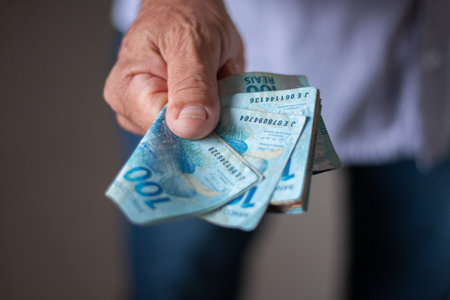 Man holding Brazilian money banknotes by hand