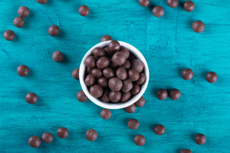Chocolate balls in white bowl on blue backgroundの写真素材