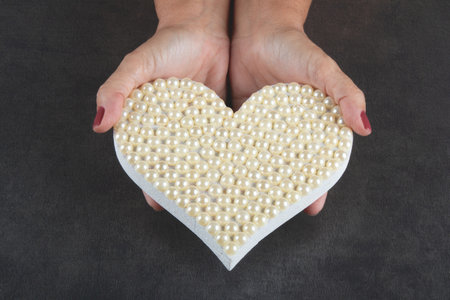 Valentine's day background with hand holding heart with white pearls