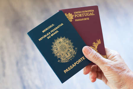 Hand holding Portuguese passport and Brazilian passport.の写真素材