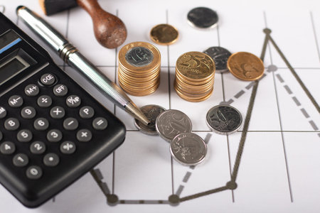 Financial graph with Brazilian coins, calculator and pen.