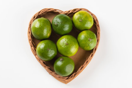 Ripe green lemon fruit in basket with heart shape.