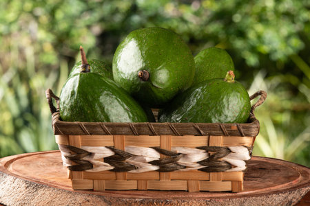 Green avocado fruit in basket on blurred background.