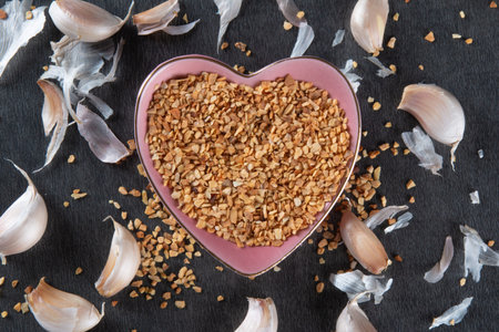 Garlic Cloves and Bulb in Heart Bowl with Dark Background.