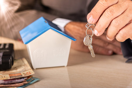 Business man holding key with small house on table. housing concept.