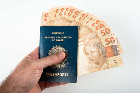 Hand holding Brazilian passport with fifty reais banknotes. Brazilian money.の写真素材