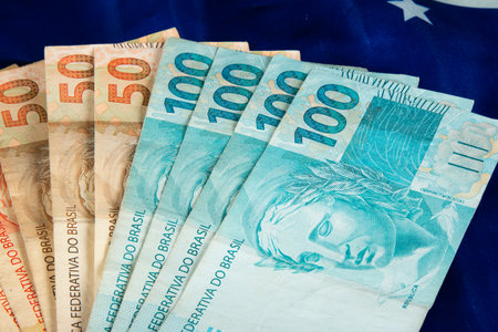 Brazilian money banknotes with Brazilian flag in the background.の写真素材