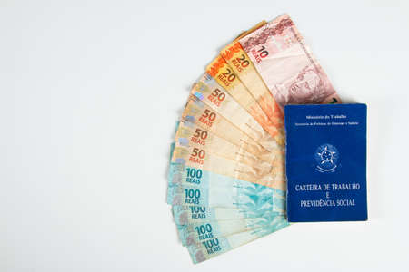 Brazilian document work and social security (Carteira de Trabalho e Previdencia Social) with Brazilian money banknotes.の写真素材