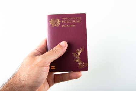 Male hand holding portuguese passport over white background.