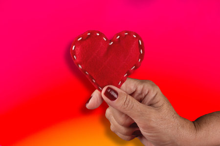 Female hand holding red hearts on red background