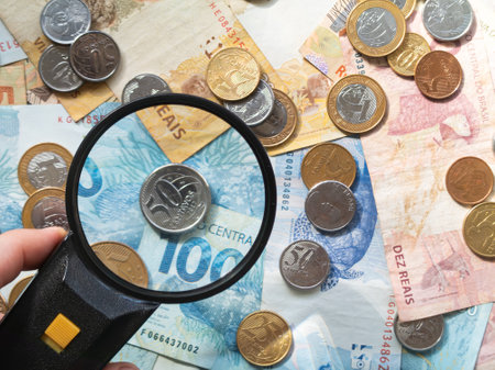 Magnifying glass over Brazilian money banknotes and coins. Finance concept.の写真素材