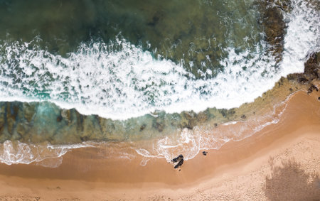 Aerial top view of sandy beach with stunning waves