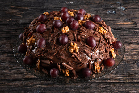 Cake with chocolate icing and grapes on a rustic background.の写真素材