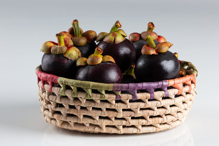 Fresh mangosteen fruit in a basket on white background.の写真素材