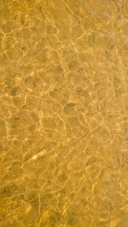 Vertical abstract background. Golden river water surface with sun reflections.の写真素材