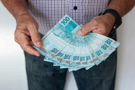 Brazilian money. Man holding fanned stack of Brazilian Real banknotes.