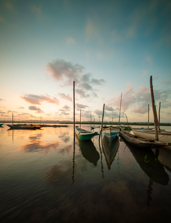 Tranquil boats moored at dusk reflections shimmer on calm water.の写真素材