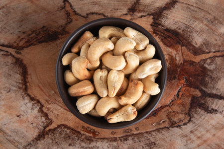 Cashews in bowl on wooden background.