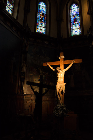 Light of the church on crucifix with its projected shadow and stained glass in the backgroundのeditorial素材