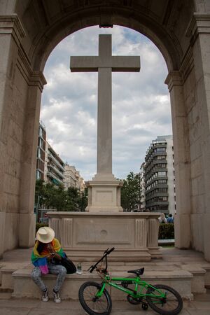 Valencia, Spain - June 16, 2018:  An assistant to gay pride day parade rests next to a large crossのeditorial素材