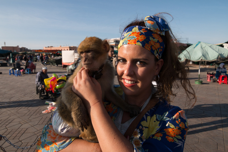 Beautiful brunette woman portrait with a headscarf and a monkey in her arms.の写真素材