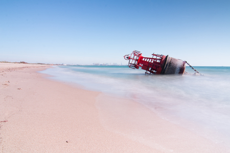 A navigation buoy stranded on the beach by the strong currents of a storm with a long exposition for a silk effectの写真素材