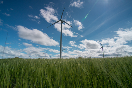 A landscape with windmills generating alternative and green energy in the wind farm on a sunny day with clouds in the sky.の写真素材