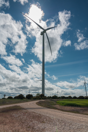 A landscape with windmills generating alternative and green energy in the wind farm on a sunny day with clouds in the sky.の写真素材