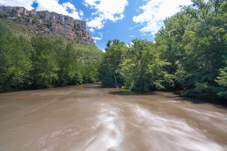 Long exposure image of the Ebro river canyon in the province of Burgos (Spain), with the flow of water with silk affection, the forest and the mountains in the background. Nature conceptの写真素材