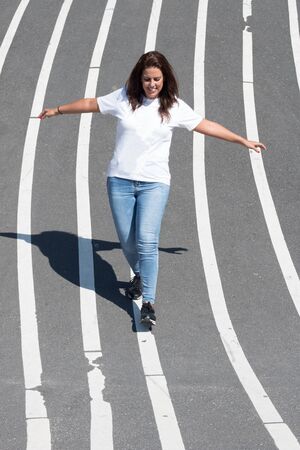 Woman balancing on a white line painted on the floor.の写真素材
