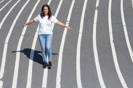 Woman balancing on a white line painted on the floor.の写真素材