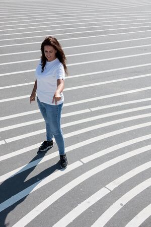 Smiling woman pointing the asphalt floor with white stripes in Superkilen Parkの写真素材