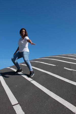 Confident woman posing over asphalt floor with white stripesの写真素材