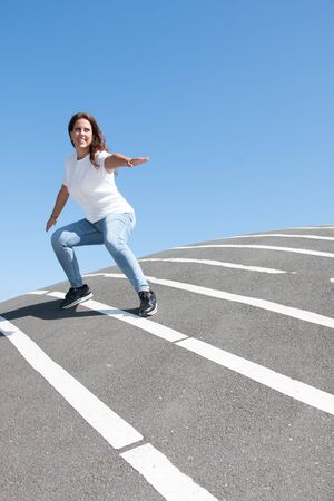 Smiling woman posing surfing over asphalt floor with white stripesの写真素材
