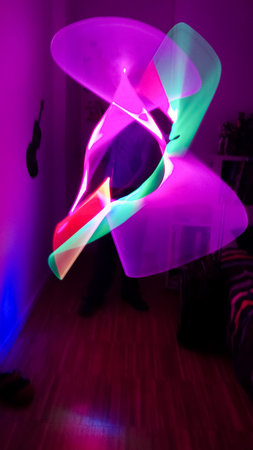 Boy playing in his room with lightsaber in various colors. Lightpainting effect