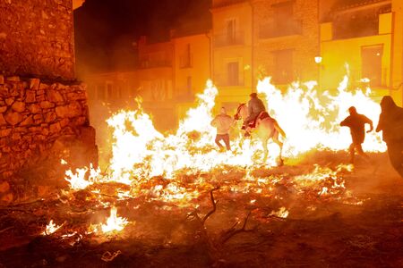 People and a man riding his horse jump over bonfires in the traditional festival of St Antonio, in Vilanova d'Alcolea, in CastellÃ³n, Spain. Festival conceptの写真素材