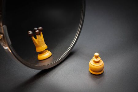 Pawn looking in the mirror and seeing himself like a king with dark background. Psychological conceptの写真素材