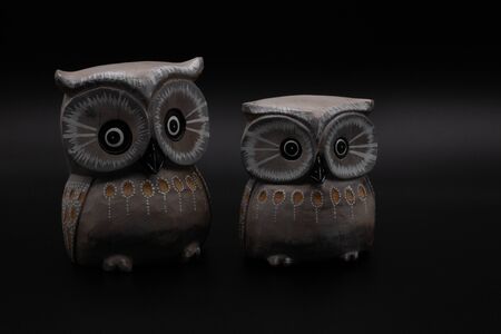 Figure of a pair of wooden owls one bigger than another on black background. Couple conceptの写真素材