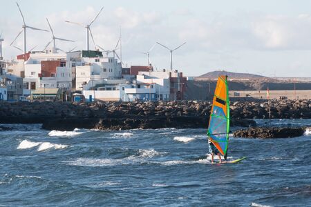 A windsurfer is racing with a little town with windmills in background. Sport conceptの写真素材
