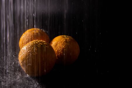 Still life of three oranges on dark background under heavy rain. Fruit conceptの写真素材