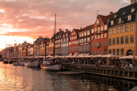 Copenhagen, Denmark - August 23, 2019: Famous Nyhavn pier with colorful buildings with people enjoying the terraces at sunset in Copenhagen, Denmarkのeditorial素材