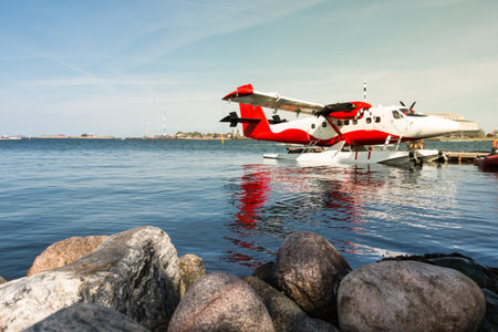 Red and white seaplane tied to a jetty in the city of Copenhagen. Aiplane concept