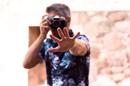A man extends his open hand towards the camera while taking a photo. Selective focus. Photography conceptの写真素材