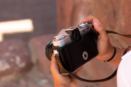 Close-up of a young woman's hands holding an old analog camera. Photography concept