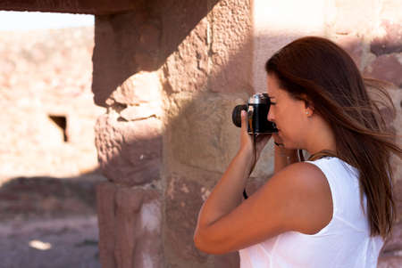 A young woman in white dress photographing with old camera on the street. Photography conceptの写真素材