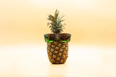 Funny pineapple with sunglasses over pastel yellow background. Summertime conceptの写真素材