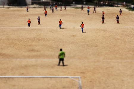 Amateur soccer match on a dirt field in a neighborhood with the tilt shift effect applied to the image. Amateur sport conceptの写真素材